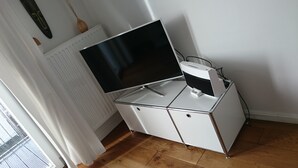 Un escritorio compacto blanco con dos niveles, y un televisor de pantalla plana en el nivel superior.