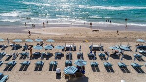 A beach with rows of blue and white striped beach umbrellas and lounge chairs. - 3 BR Apartment with amazing View,  Pool and  Gym (Hollywood)