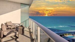A balcony with a view of the ocean at sunset, wicker furniture, and a pool area. - Insane Ocean View Balcony| Beachfront Resort+Pools (Hollywood)