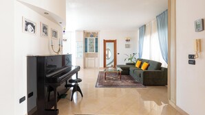 A living room with a piano, a sofa, a coffee table, and a mirror. - 4046 Villa Del Vecchio by Barbarhouse (Ostuni)