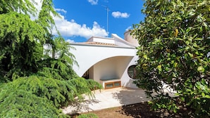 A modern house with a unique curved roof, surrounded by lush greenery. - 4046 Villa Del Vecchio by Barbarhouse (Ostuni)