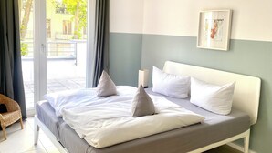 A bedroom with a bed, pillows, a bedside table, and a window with curtains. - Apartment Schuppen III with balcony and terrace (Rerik)