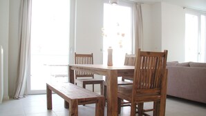A dining area with a wooden table and chairs, a bench, and a view of the outdoors through large windows. - Apartment Schuppen III with balcony and terrace (Rerik)