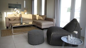 A modern living room with a sofa, ottoman, and a glass coffee table. - Apartment Schuppen III with balcony and terrace (Rerik)
