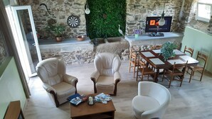 A cozy living room with a stone wall, leather armchairs, a wooden coffee table, and a TV on a stand. - L Abreuvoir DU Leffo Entre MER ET Campagne. Ressourcez Vous Avec vos Animaux (Allineuc)