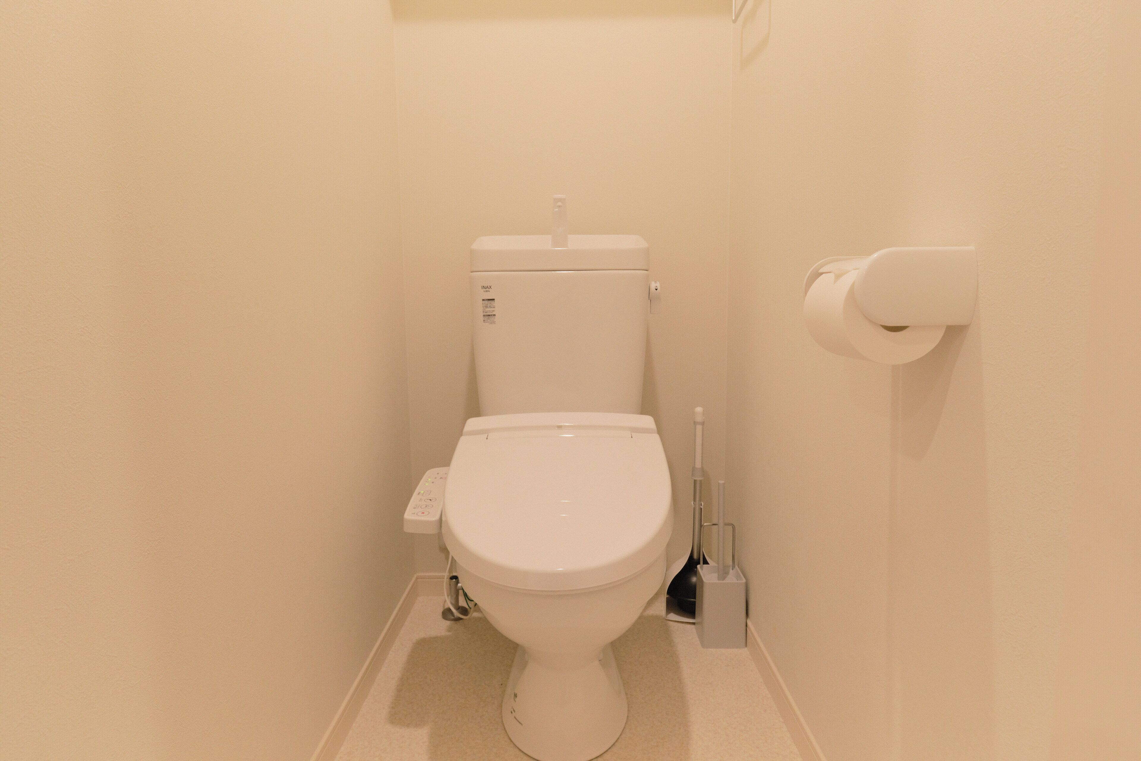 Um banheiro pequeno e branco com vaso sanitário, rolo de papel higiênico e bidê.