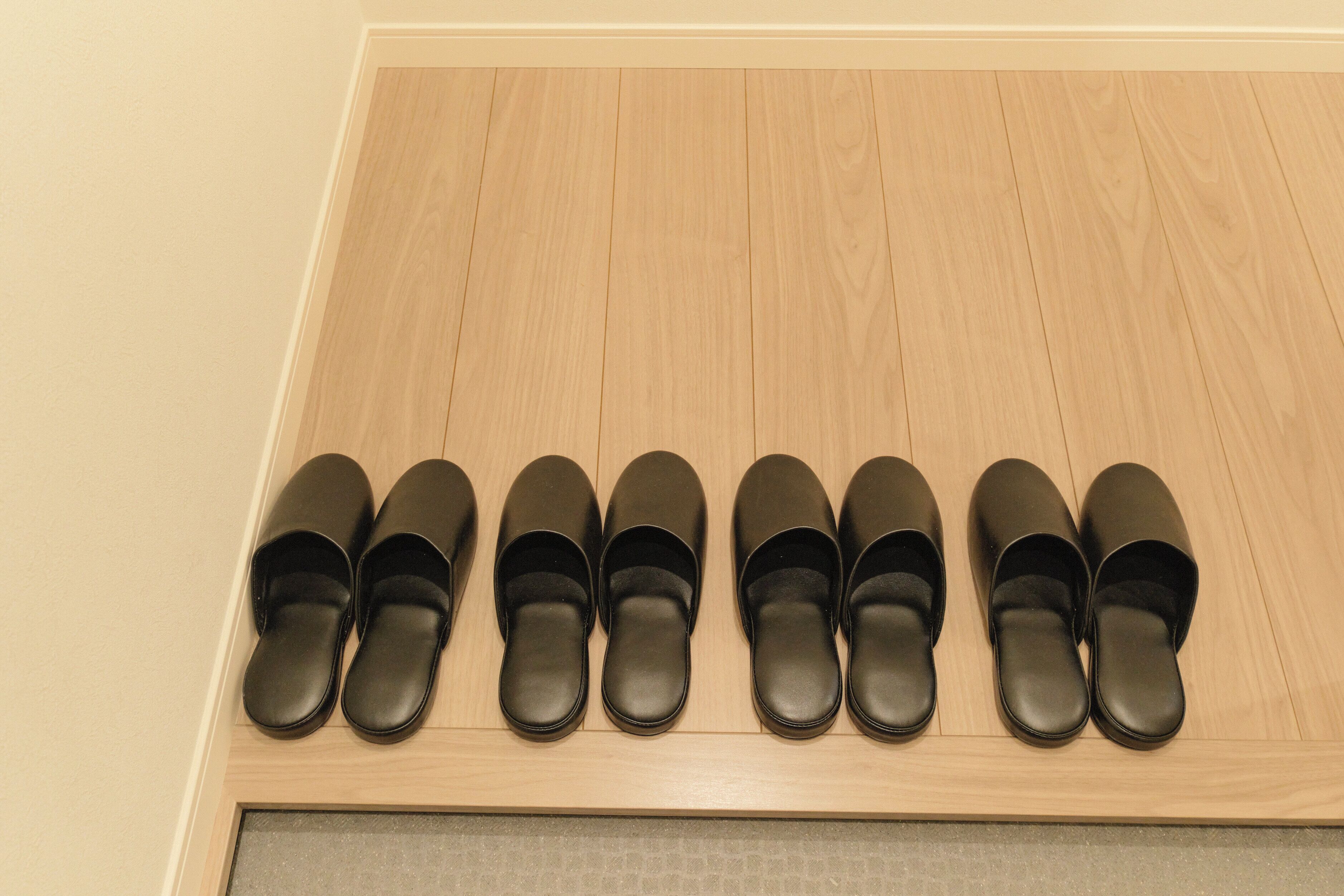 A wooden shoe rack with black shoes.