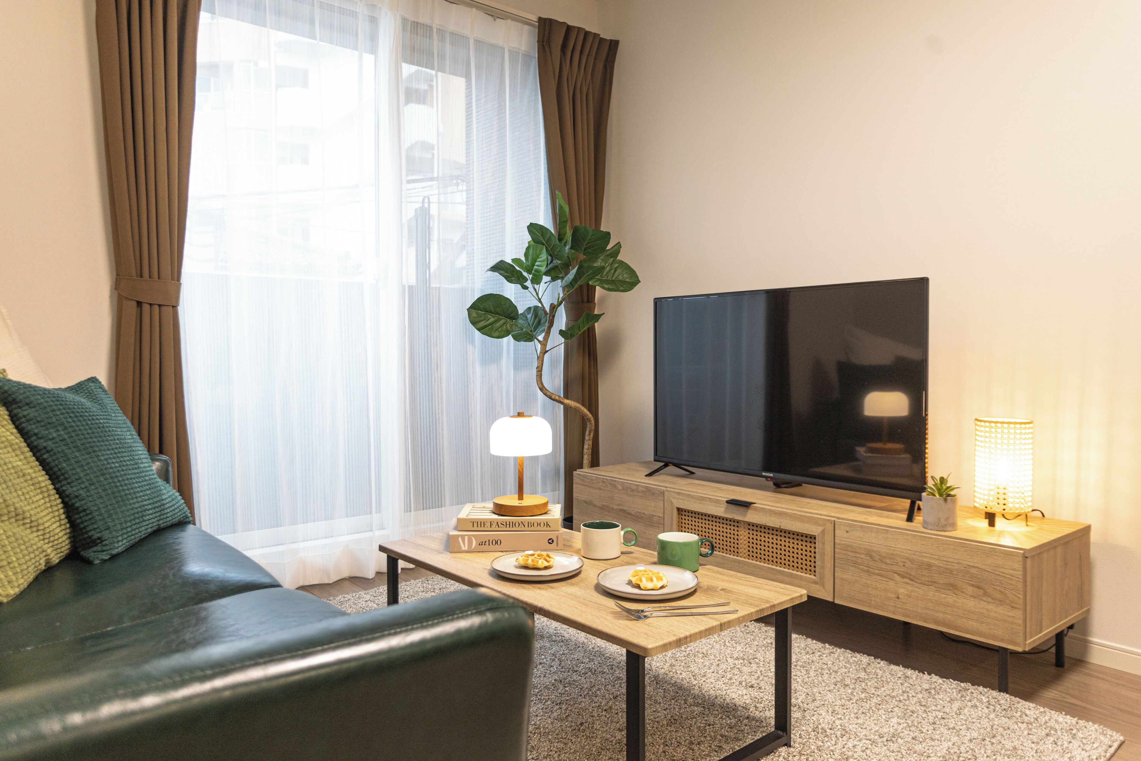 En moderne stue med sofa, sofabord, fjernsyn og en plante.