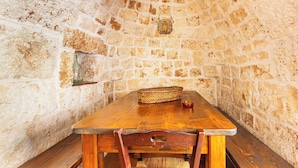 A rustic stone-walled room with a wooden table and bench. - 3834 Villa La Bianca Ostuni by Barbarhouse (Carovigno)