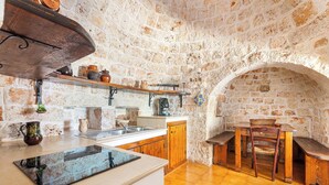 A rustic kitchen with stone walls, wooden furniture, and a tiled floor. - 3834 Villa La Bianca Ostuni by Barbarhouse (Carovigno)