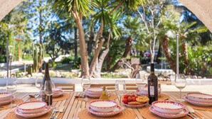 An outdoor dining area with tables set for a meal, surrounded by palm trees and a clear sky. - 3834 Villa La Bianca Ostuni by Barbarhouse (Carovigno)