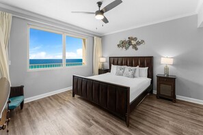 A bedroom with a large window, a bed, a ceiling fan, and a nightstand. - Shores of Panama Chic 2-BD Beachfront Resort Condo! (Panama City Beach)