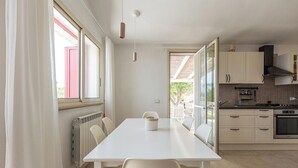 A modern kitchen with white cabinets, a white countertop, and a dining area with a white table and chairs. - 4099 Villa Maste by Barbarhouse (Carovigno)
