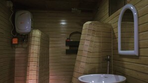 Casa de banho pequena e fechada com uma pia branca, um espelho e um dispensador de sabão.