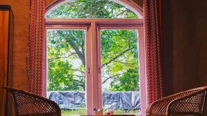 A room with two wicker chairs, a small table, and a window with curtains.