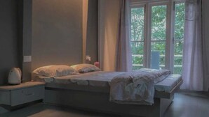 A bedroom with a bed, bedside table, and a window with curtains.