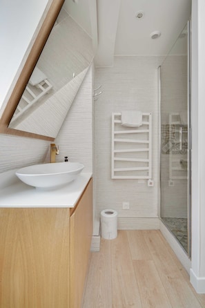A modern bathroom with a large mirror, a vessel sink, a towel rack, and a shower area. - Résidence Paris CHOISEUL (Paris)