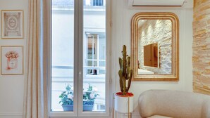 Una stanza con un'ampia finestra, un cactus in vaso, uno specchio e quadri appesi al muro.