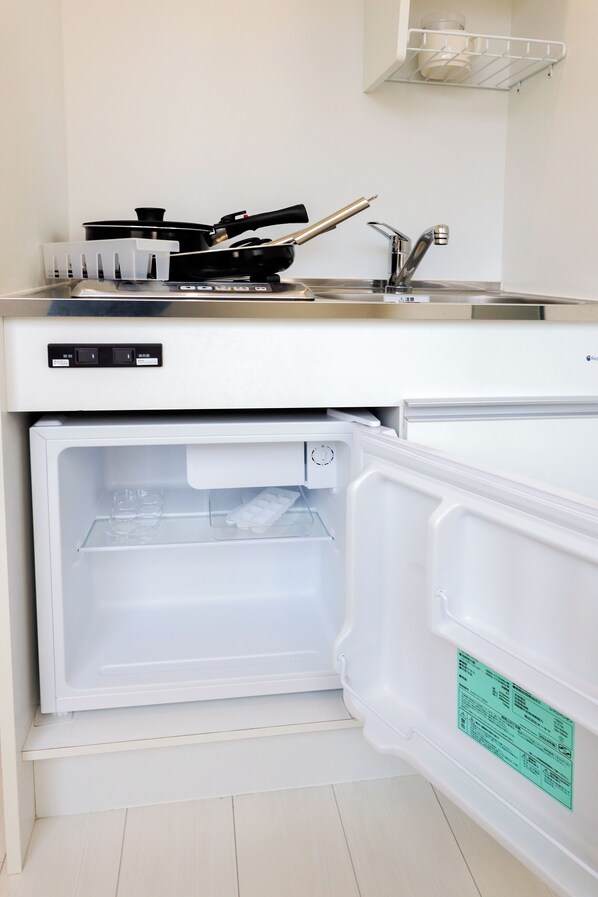 A compact kitchen with a built-in refrigerator and a microwave. - Nano Kamiochiai (Tokyo)