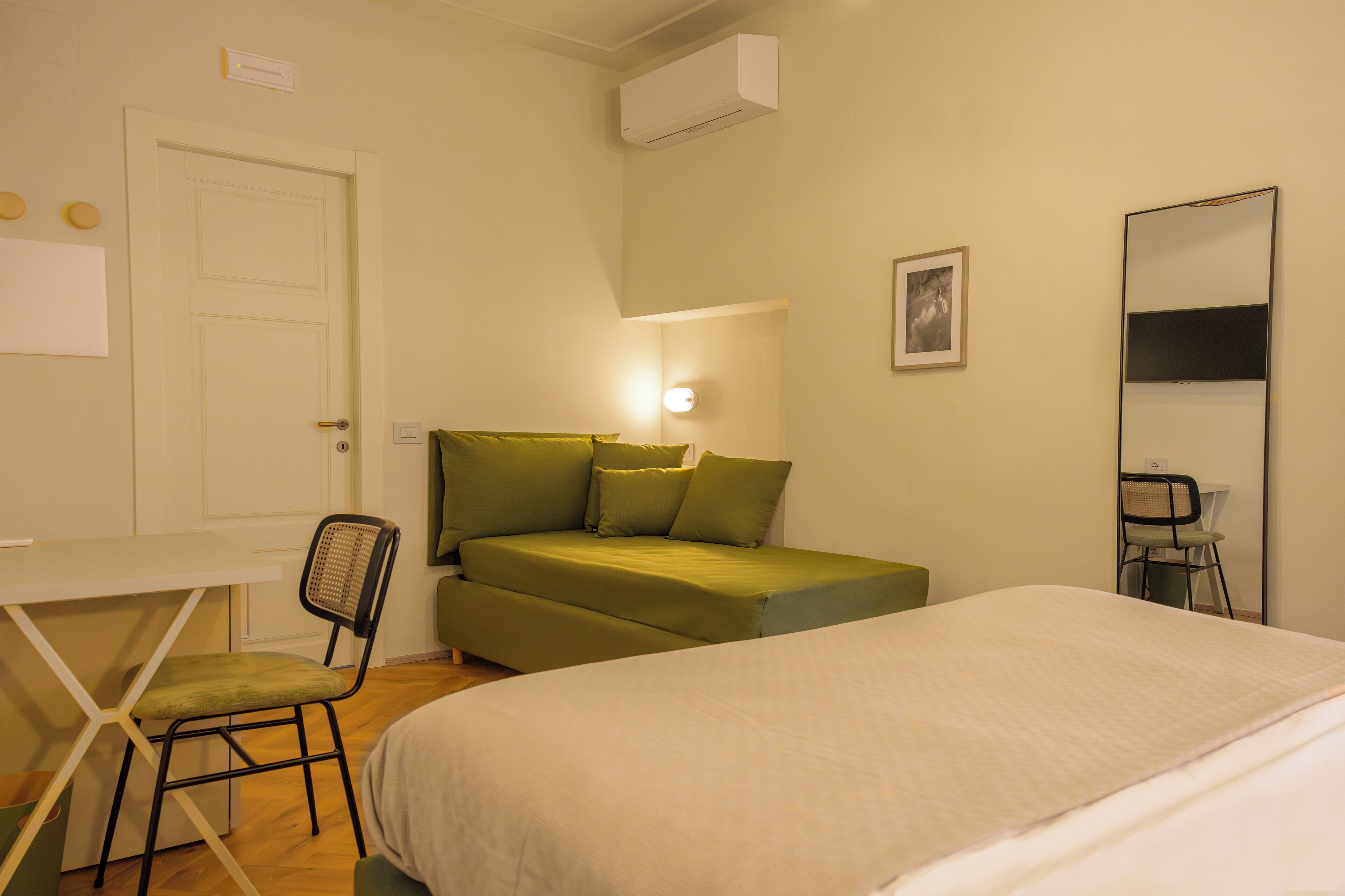 Quarto com cama, escrivaninha, cadeira, sofá e espelho.