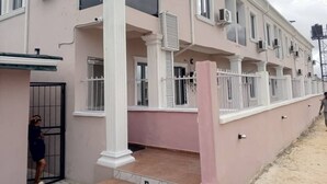 A multi-story building with a pink facade, white columns, and multiple air conditioning units. - Tristar Hotel & Suites  (Lekki)