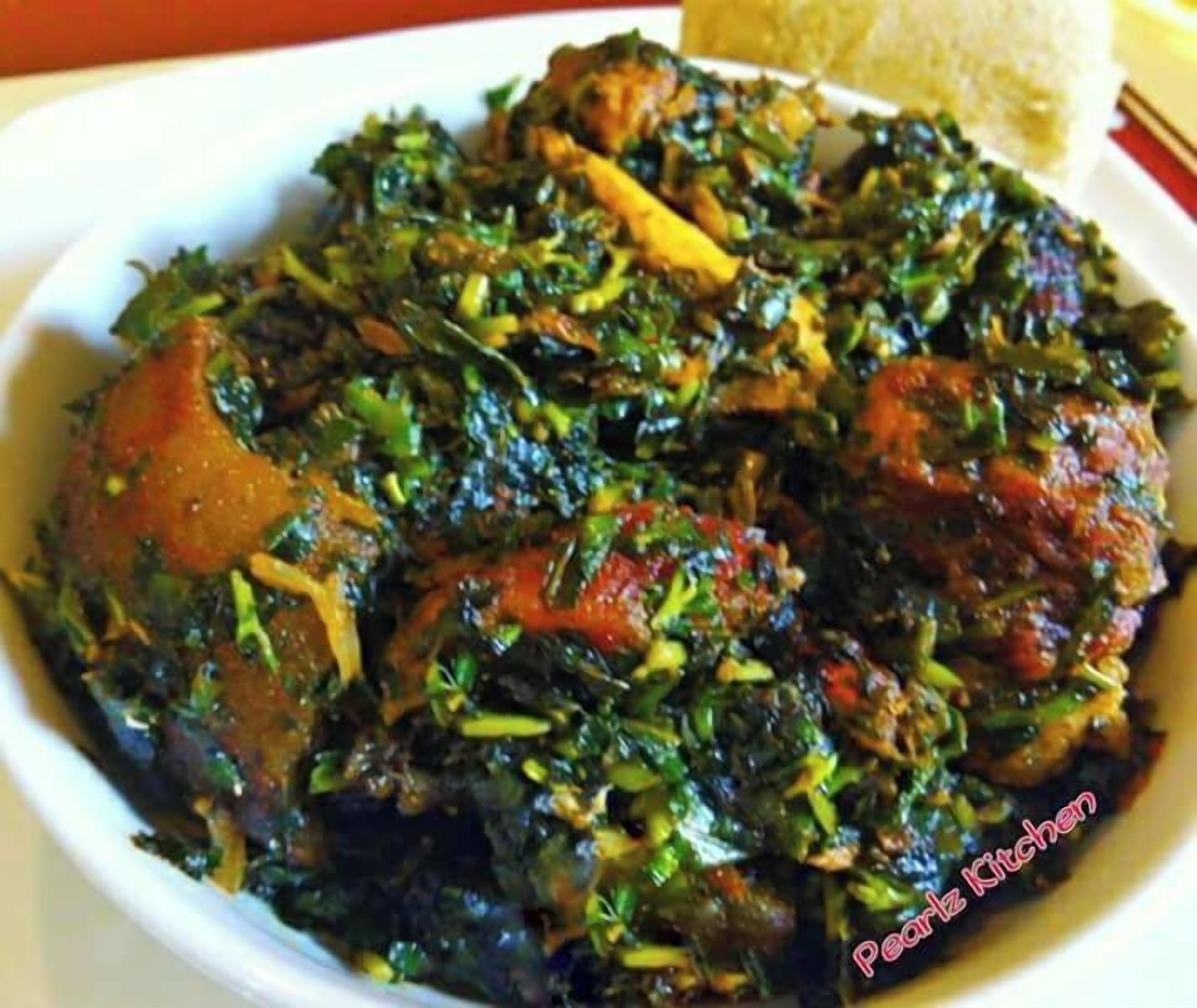 A dish with greens, meat, and tomatoes on a white plate.