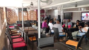 A restaurant with outdoor seating, tables, chairs, and fans. - Tristar Hotel & Suites  (Lekki)