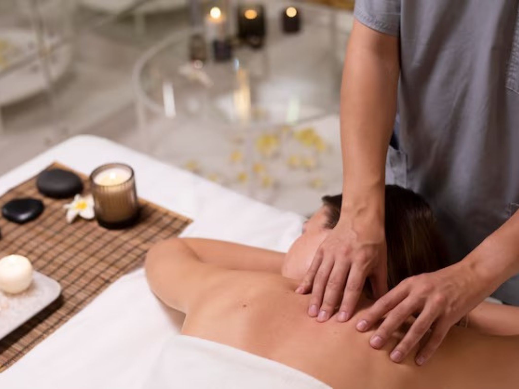 Eine Massageanwendung: Eine Person liegt dabei überstürzt auf einer Liege und erhält eine Rückenmassage.