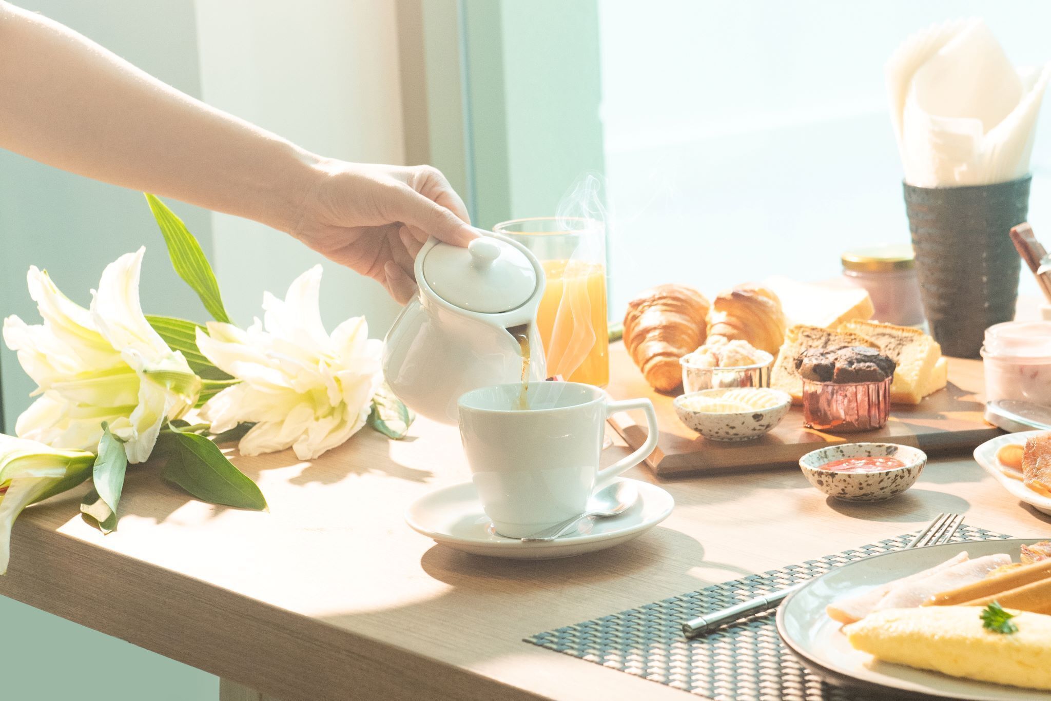 A breakfast table with a cup of coffee, croissants, and a glass of orange juice.