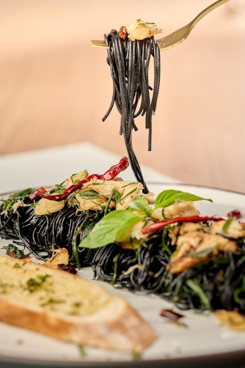 A plate of black noodles garnished with herbs and vegetables.