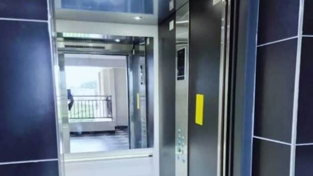 An elevator interior with a metallic finish and a yellow emergency exit sign. - Lux Suites Lakira Shades Ongata Rongai (Ongata Rongai)