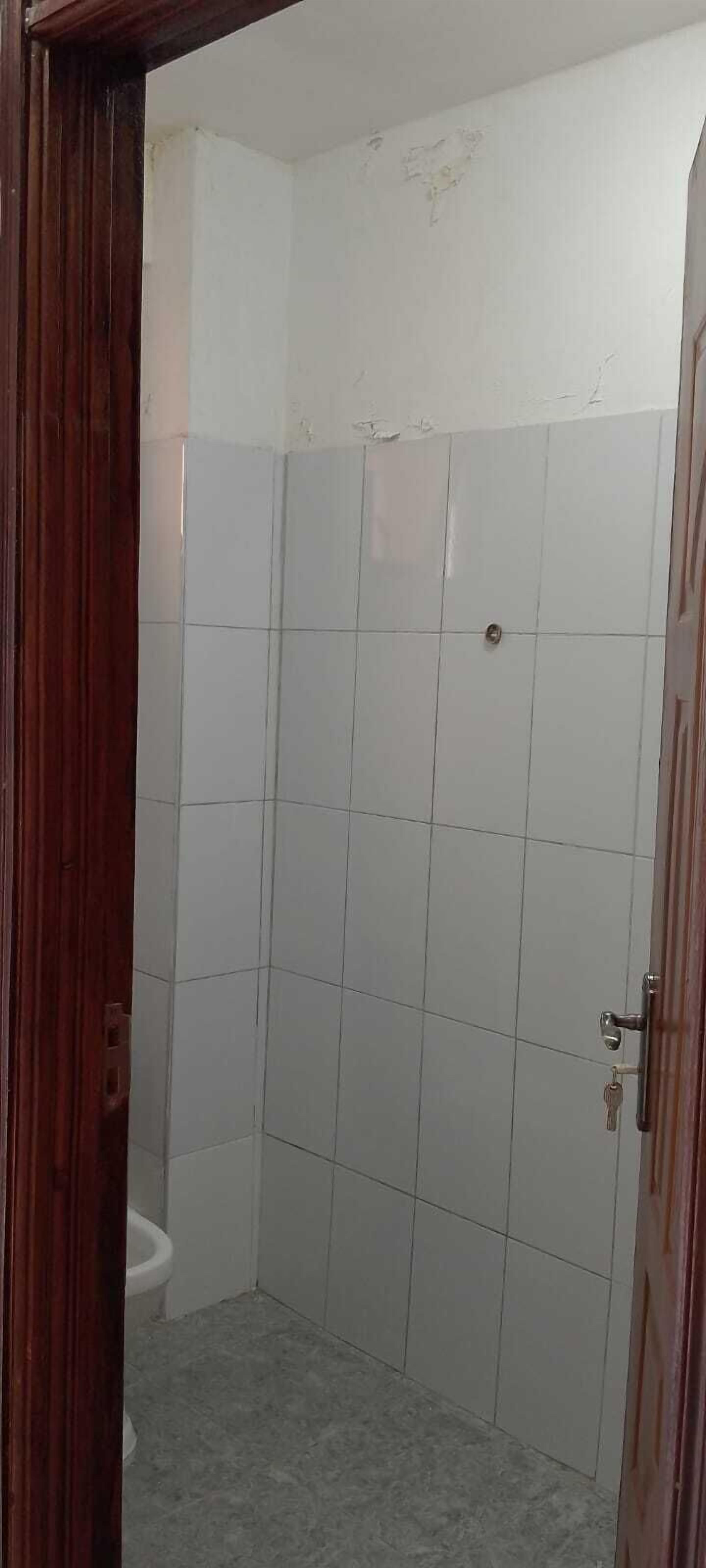 A bathroom with white tiled walls and a wooden door.
