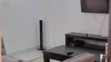 Un salon comprenant un canapé, une table basse, un téléviseur et un téléviseur à écran plat fixé au mur.