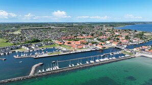 Vue aérienne d’une ville côtière avec un port de plaisance, des maisons et une église.