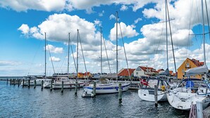 Un port de plaisance où de nombreux voiliers sont amarrés à des quais en bois, entouré de bâtiments aux toits rouges et jaunes.