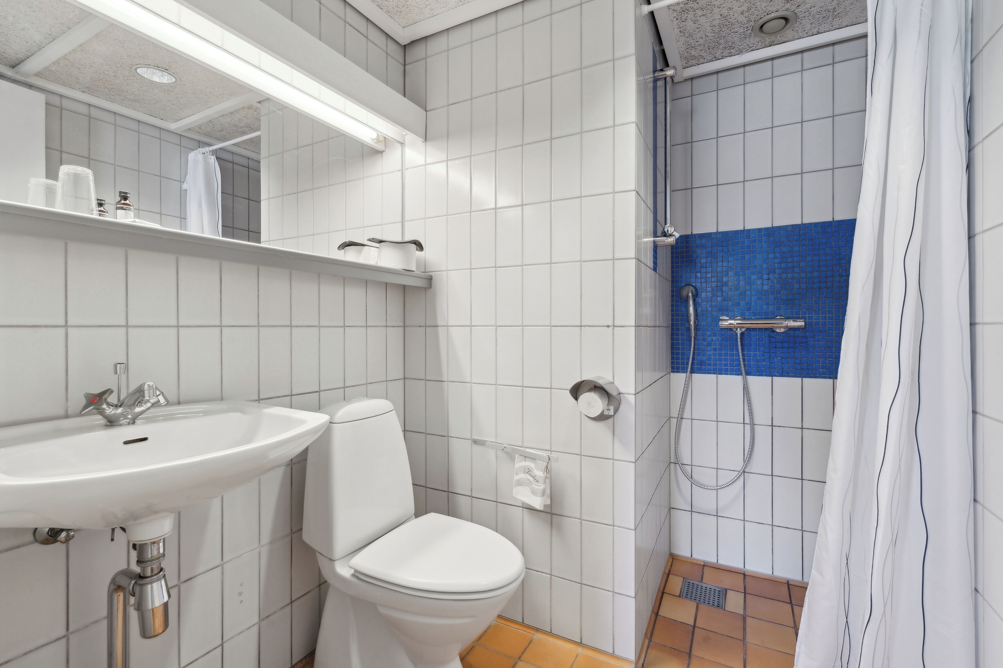A bathroom with a white sink, toilet, and shower.