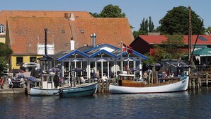 Un port où des bateaux sont amarrés, un bâtiment avec un toit rouge et un drapeau.