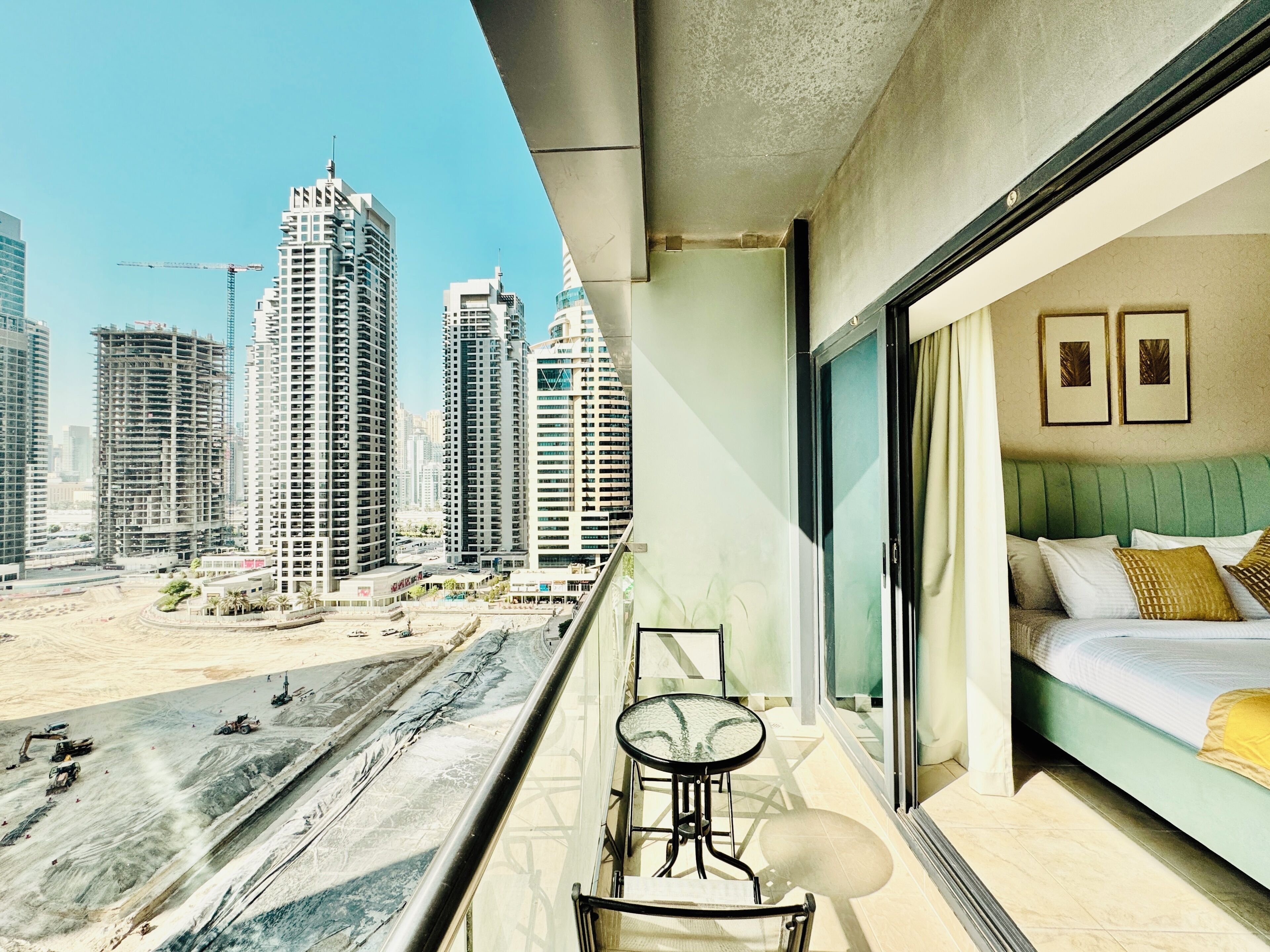 Un balcone con vista sulla città, un letto con cuscini e un tavolo con una sedia.