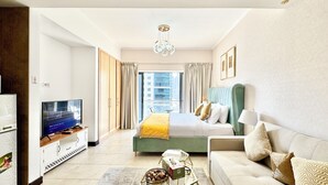 A modern hotel room with a large bed, a sofa, a TV, and a view of the city. - Cosmos Living - Goldcrest Views1  (Dubai)