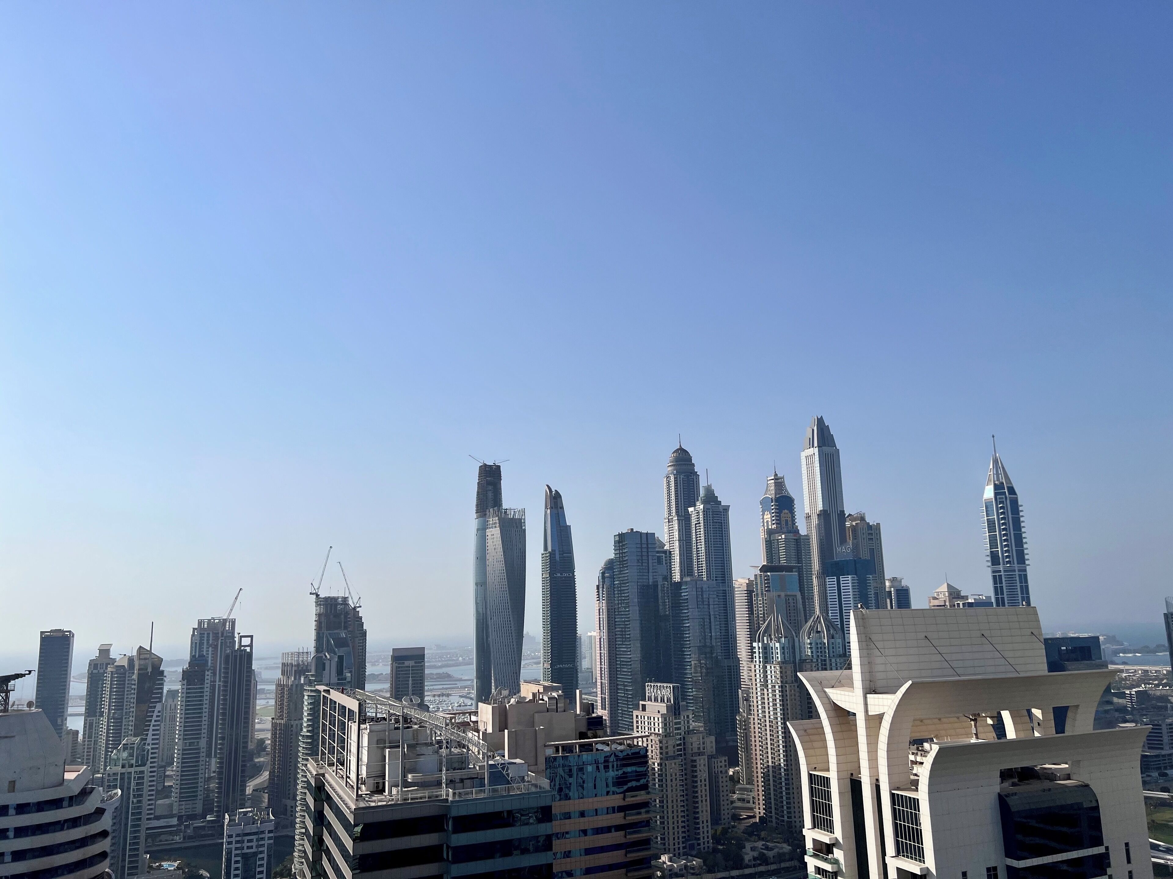 A cityscape with modern high-rise buildings, including a distinctive tower with a pointed top.