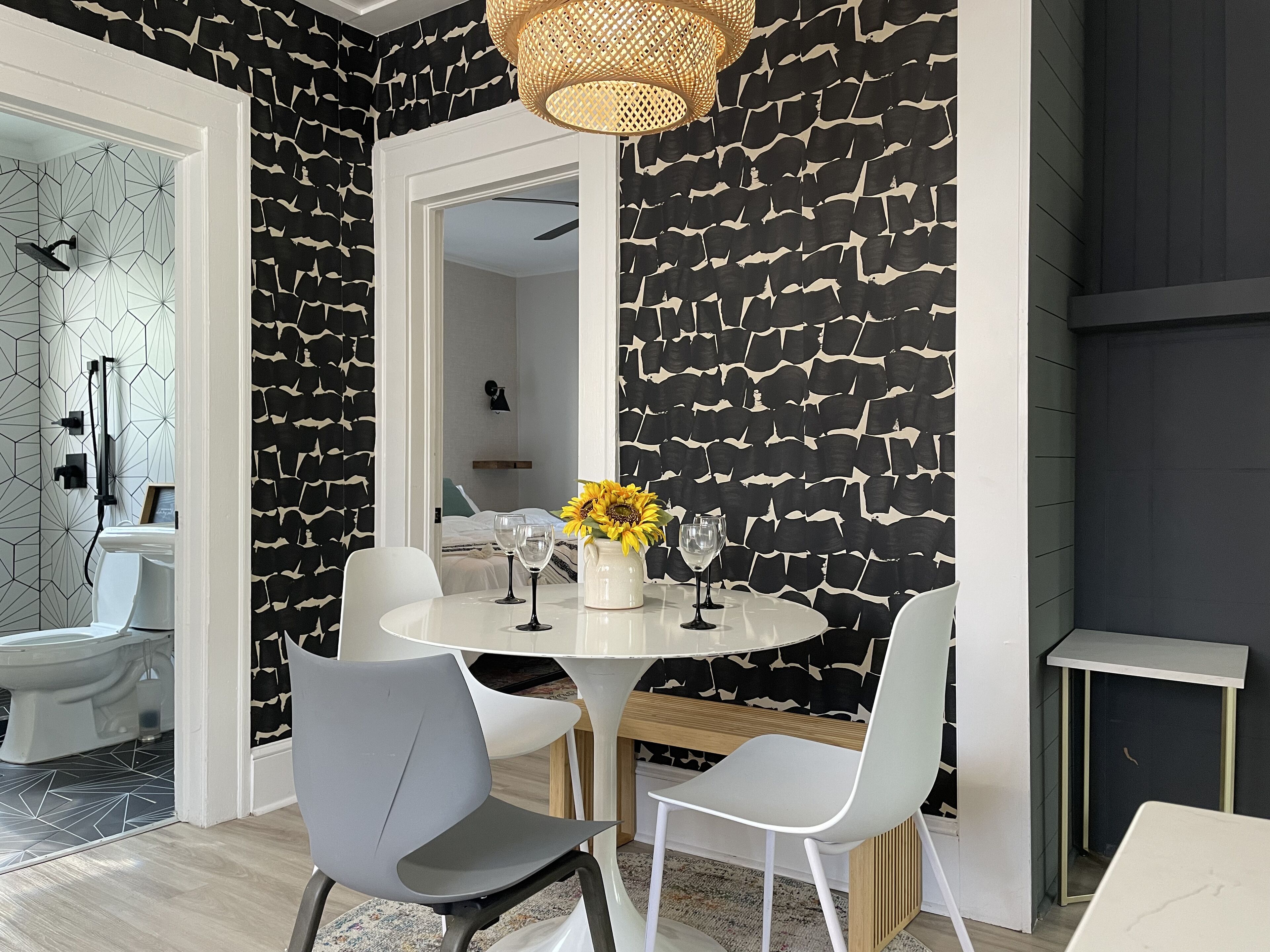 A dining area with a round table, two grey chairs, and a vase with sunflowers.