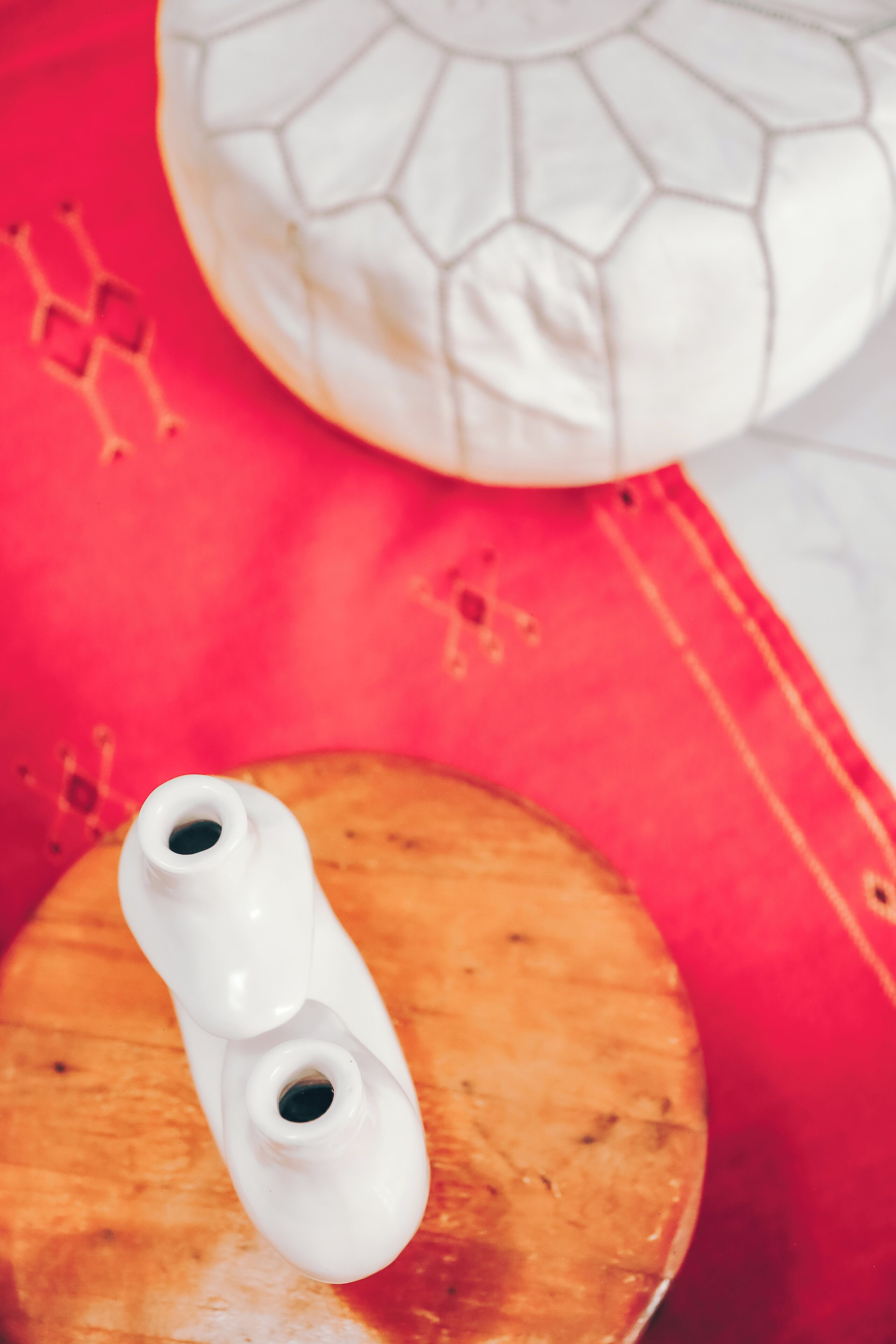 A white ceramic object with two holes, placed on a wooden surface.