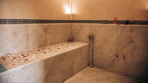 A bathroom with a marble bathtub, a shower, and a decorative tile border. - Riad Tislite & Spa (Marrakech)