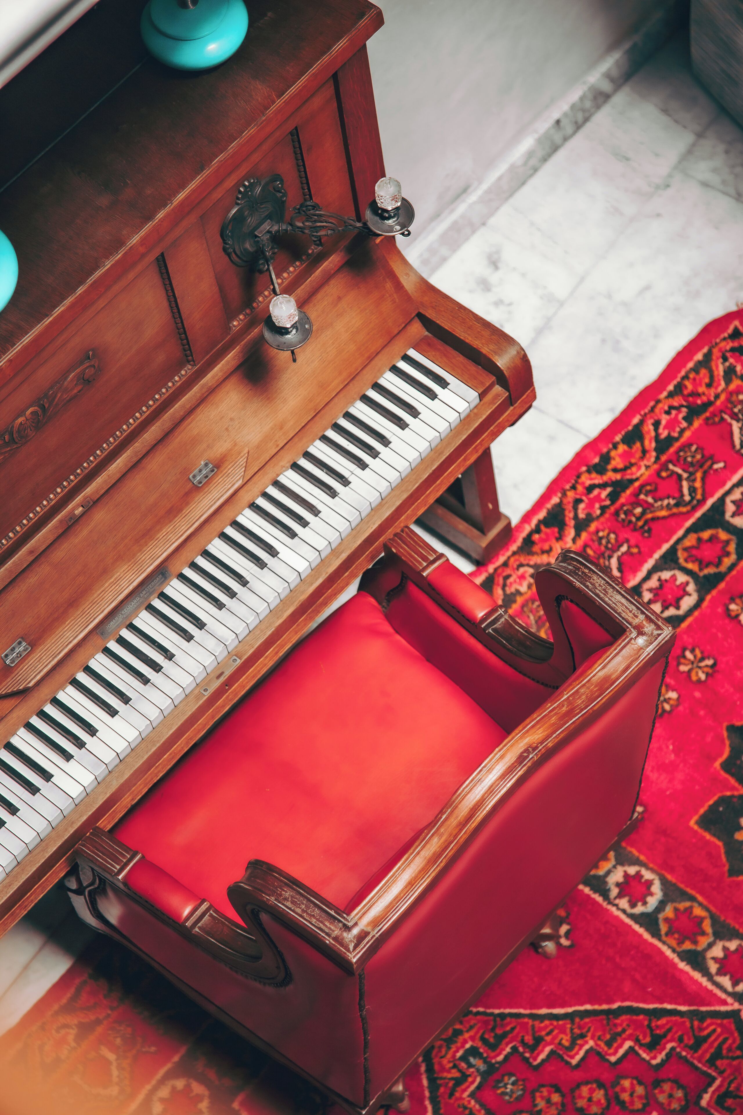 A grand piano with a red bench in a room with patterned carpet.
