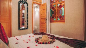 A bedroom with a bed, a mirror, and a decorative window. - Riad Tislite & Spa (Marrakech)