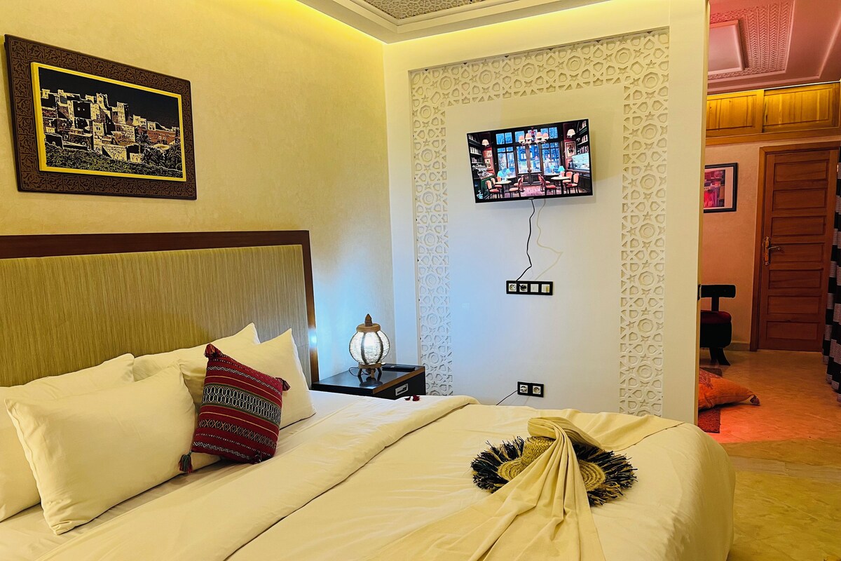 Une chambre d’hôtel équipée d’un lit, d’un téléviseur fixé au mur et d’un panneau décoratif mural.