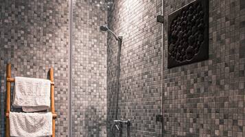 Une salle de bain moderne avec une douche à parois de verre, un porte-serviettes en bois et des toilettes avec une étiquette bleue.