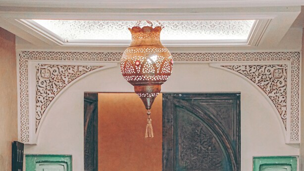 A staircase with ornate white railings, a green door with intricate carvings, and a hanging lantern. - Riad Tislite & Spa (Marrakech)