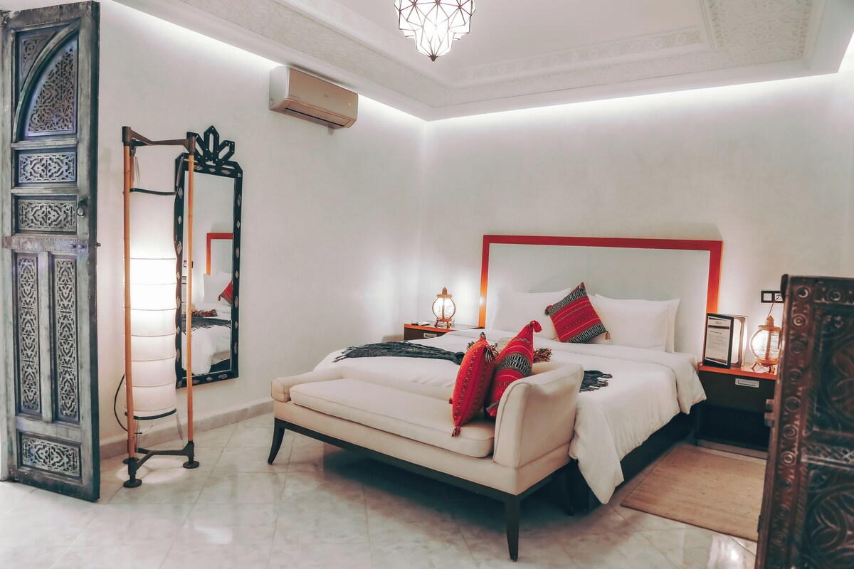 A bedroom with a bed, a nightstand, a mirror, and a decorative door.