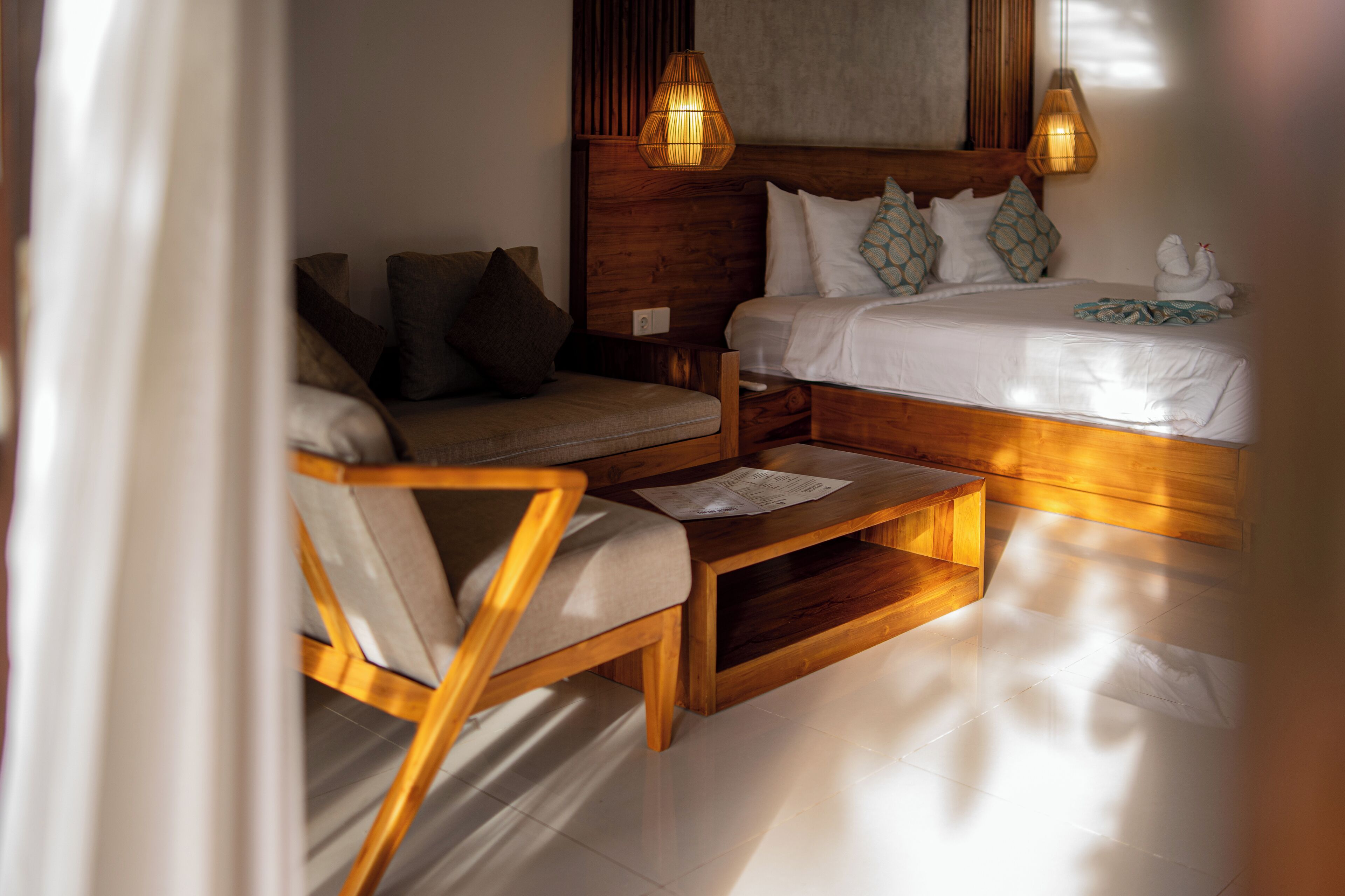 A bedroom with a wooden bed, a wooden nightstand, a wooden chair, and a wooden coffee table.